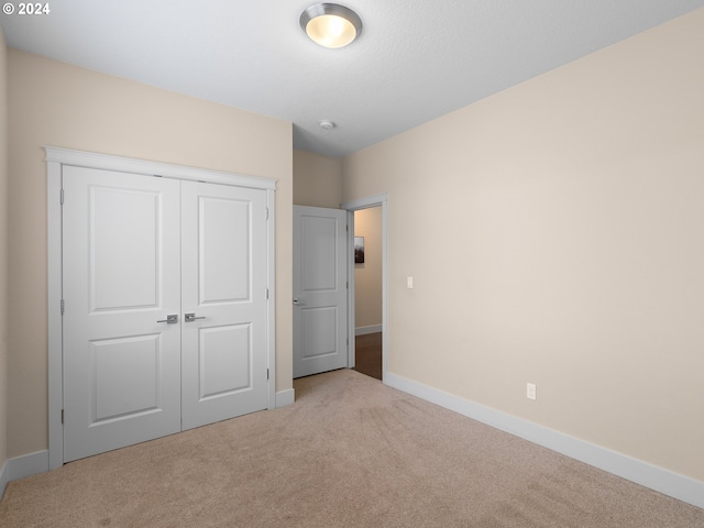 unfurnished bedroom with a closet and light colored carpet