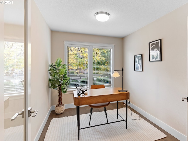 office space with a wealth of natural light, dark wood-type flooring, and a textured ceiling