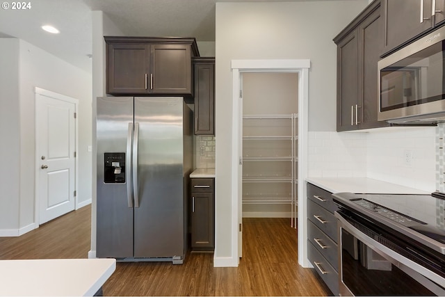 kitchen with hardwood / wood-style floors, appliances with stainless steel finishes, dark brown cabinets, and tasteful backsplash