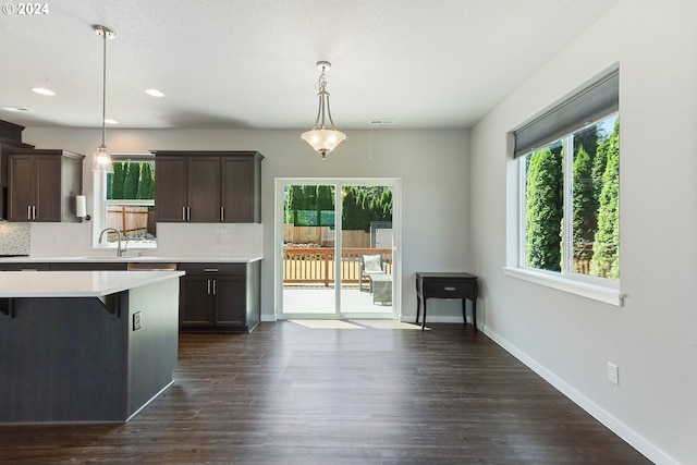 kitchen featuring dark wood-type flooring, pendant lighting, decorative backsplash, and dark brown cabinetry