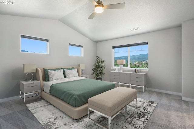 bedroom featuring a mountain view, light carpet, lofted ceiling, ceiling fan, and a textured ceiling