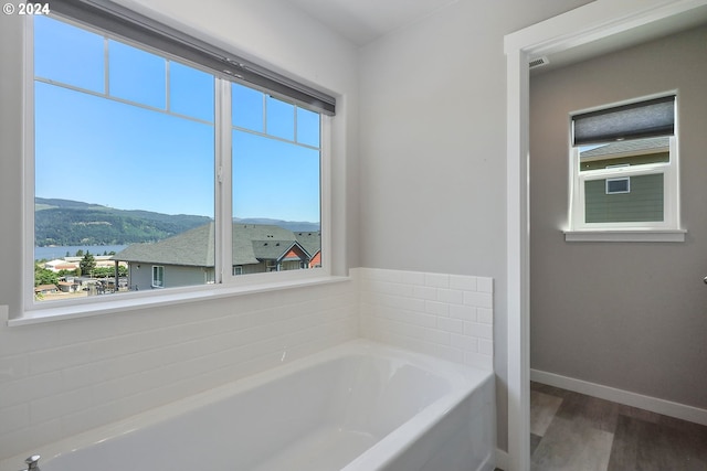 bathroom with hardwood / wood-style flooring, a bathing tub, and a mountain view