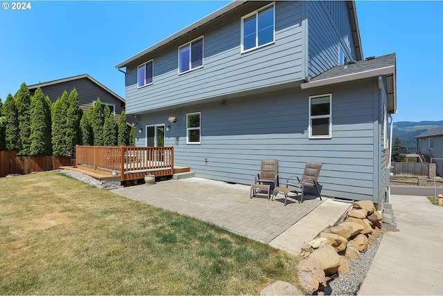 back of house with a wooden deck, a lawn, and a patio area