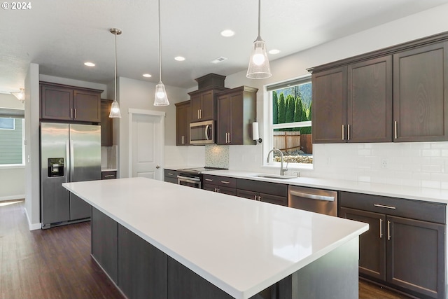 kitchen featuring a kitchen island, stainless steel appliances, decorative backsplash, and sink