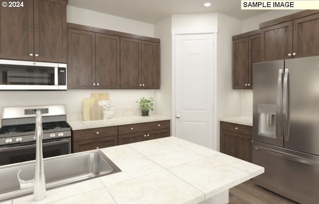 kitchen with recessed lighting, stainless steel appliances, dark brown cabinets, and tile counters