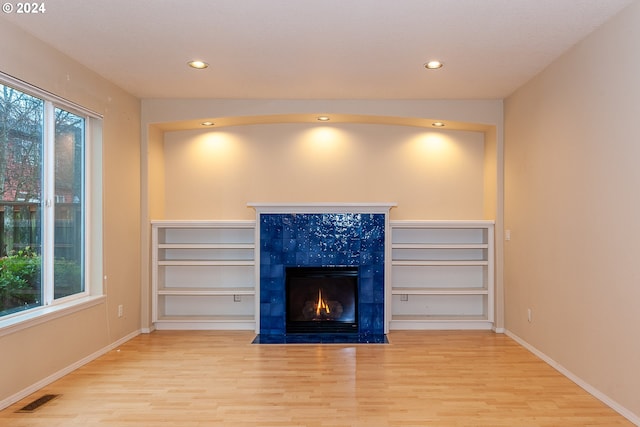 unfurnished living room with light hardwood / wood-style flooring and a tiled fireplace