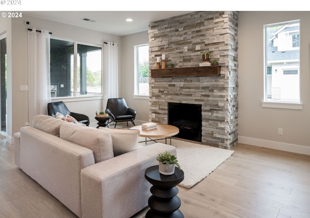 living room featuring a wealth of natural light, a fireplace, and light wood-type flooring