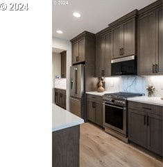 kitchen featuring tasteful backsplash, dark brown cabinets, stainless steel appliances, and light wood-type flooring