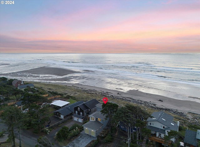 aerial view at dusk with a view of the beach and a water view