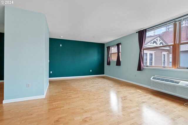 empty room featuring a wall unit AC and light wood-type flooring