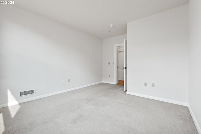 unfurnished room with carpet floors, visible vents, and baseboards