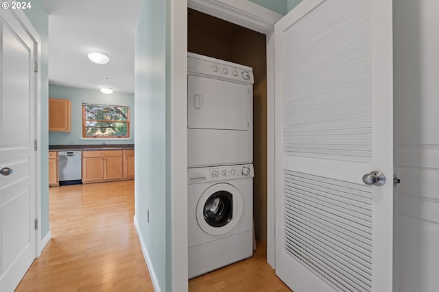 laundry area with laundry area, light wood-style flooring, and stacked washer and clothes dryer