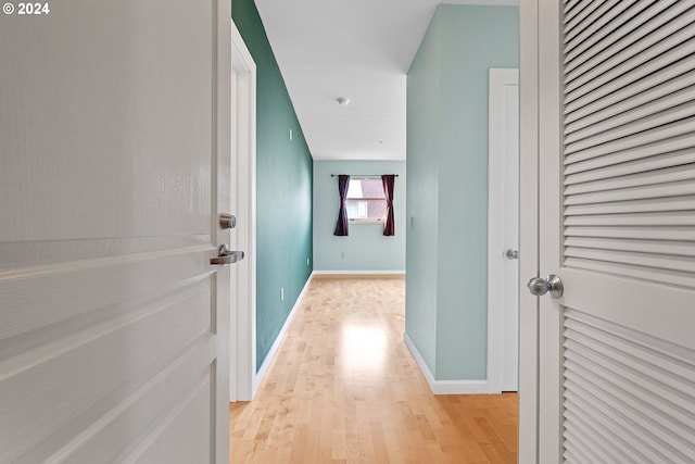 corridor with light wood-style flooring and baseboards