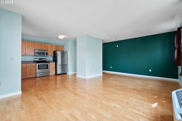 kitchen with light wood-type flooring, baseboards, stainless steel appliances, and open floor plan