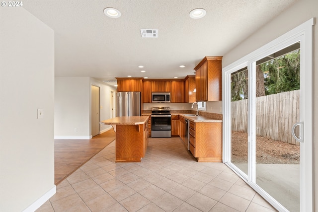 kitchen with a kitchen breakfast bar, stainless steel appliances, sink, light hardwood / wood-style floors, and a kitchen island