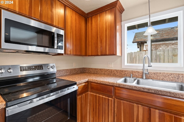 kitchen with a textured ceiling, sink, and stainless steel appliances