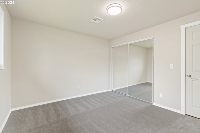 unfurnished bedroom with carpet, a textured ceiling, and a closet