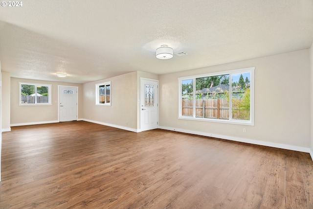 unfurnished living room featuring a textured ceiling and dark hardwood / wood-style flooring