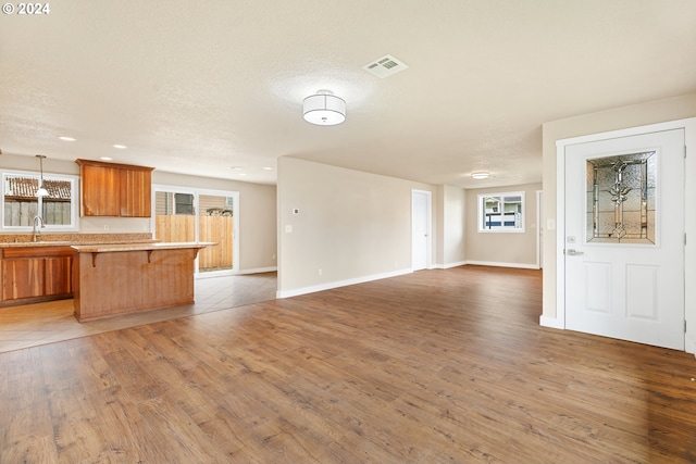 kitchen with pendant lighting, dark wood-type flooring, sink, a textured ceiling, and a kitchen bar