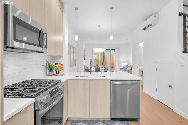 kitchen featuring a wall mounted AC, kitchen peninsula, sink, appliances with stainless steel finishes, and light brown cabinets