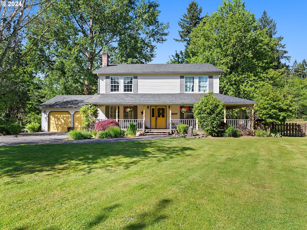 view of front of house featuring a garage, covered porch, and a front lawn