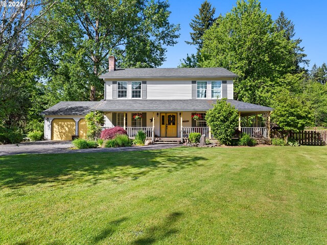 view of front of house featuring a garage, covered porch, and a front lawn