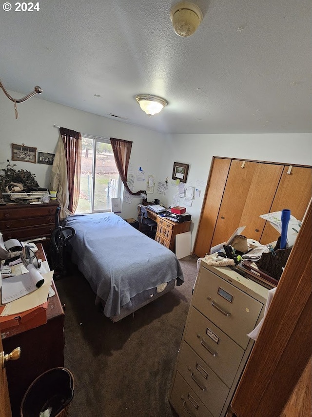 bedroom with dark carpet and a textured ceiling