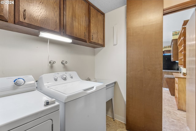 laundry room with a textured ceiling, cabinets, and separate washer and dryer