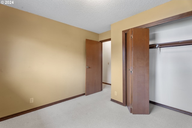 unfurnished bedroom featuring light carpet, a textured ceiling, and a closet