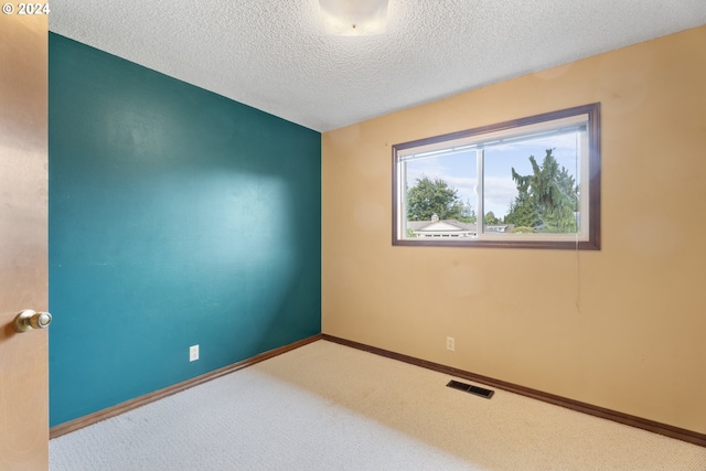 unfurnished room with carpet and a textured ceiling