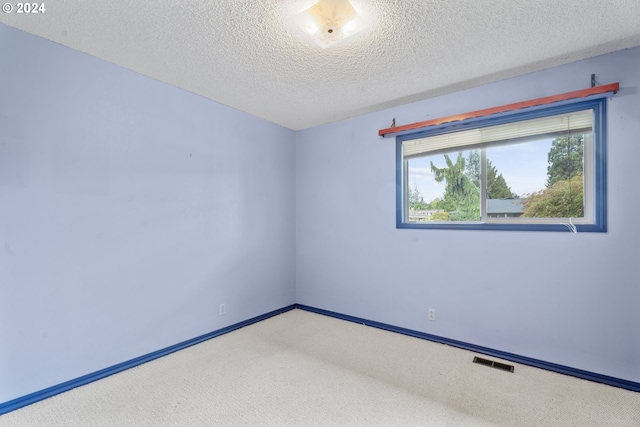 empty room featuring a textured ceiling and light colored carpet