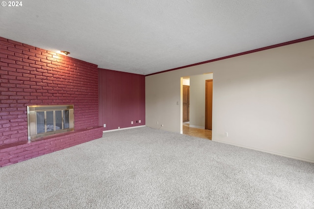 unfurnished living room featuring a textured ceiling, crown molding, a brick fireplace, and carpet floors