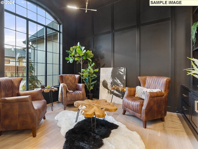 living area with a towering ceiling, plenty of natural light, and hardwood / wood-style flooring