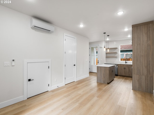 kitchen featuring a wall mounted AC, dishwasher, hanging light fixtures, a kitchen island, and light hardwood / wood-style flooring