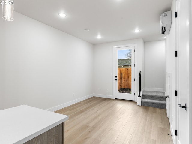 interior space featuring a wall mounted AC and light hardwood / wood-style flooring