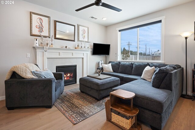 living room with a fireplace, ceiling fan, and light hardwood / wood-style flooring