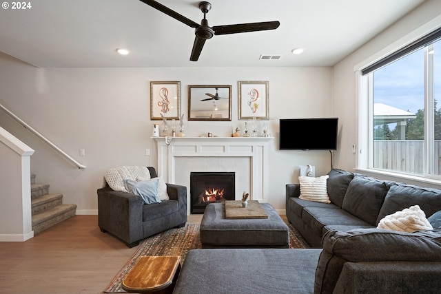 living room with a tiled fireplace, ceiling fan, and hardwood / wood-style floors