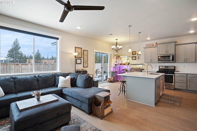 living room featuring light hardwood / wood-style flooring, ceiling fan with notable chandelier, and sink