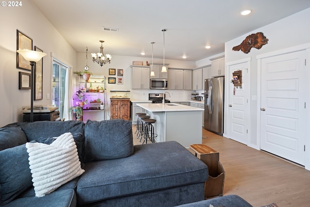 living room with light hardwood / wood-style floors, sink, and a chandelier