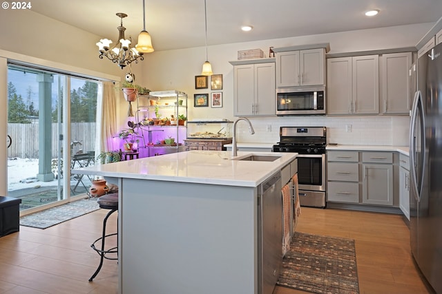 kitchen featuring pendant lighting, gray cabinetry, stainless steel appliances, and light hardwood / wood-style flooring