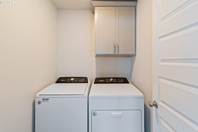 clothes washing area with cabinets and washing machine and clothes dryer