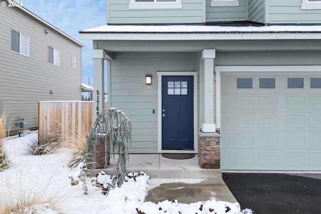 snow covered property entrance with a garage