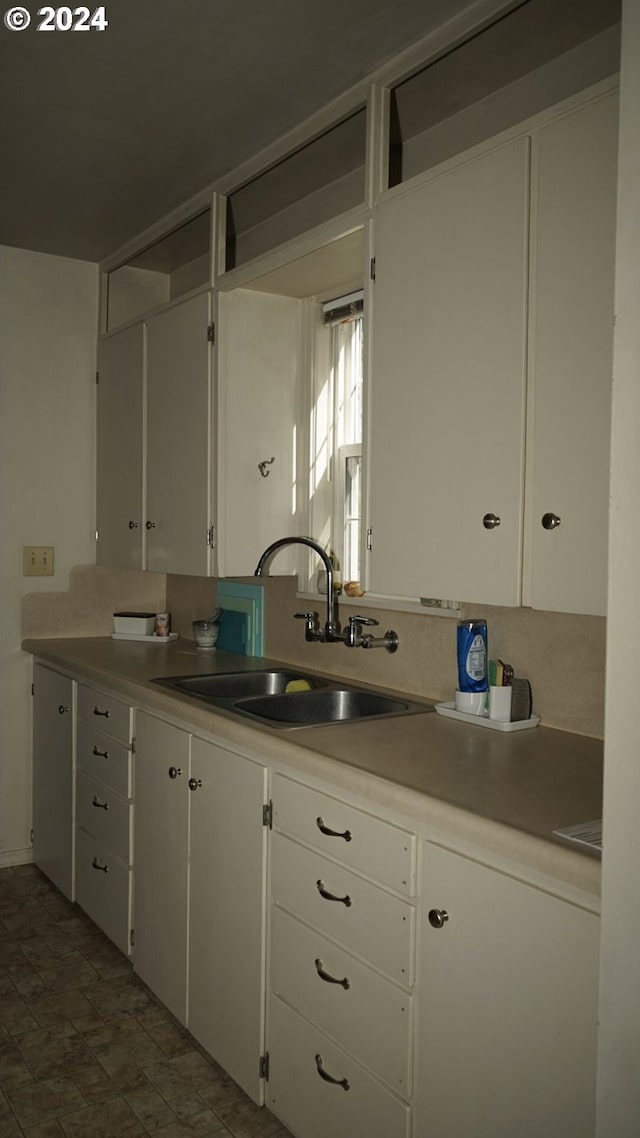 kitchen featuring white cabinets, sink, and tasteful backsplash