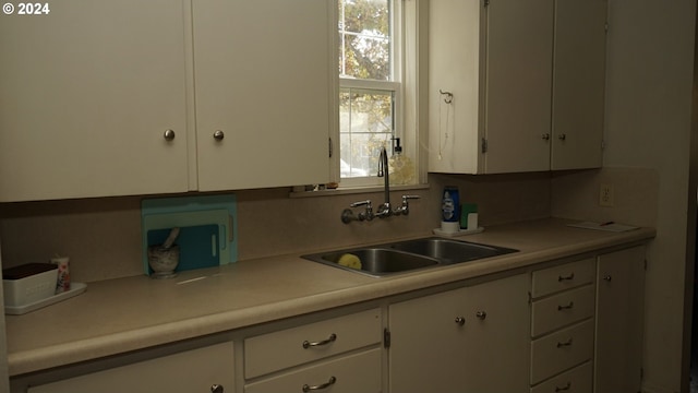 kitchen with white cabinetry, decorative backsplash, and sink