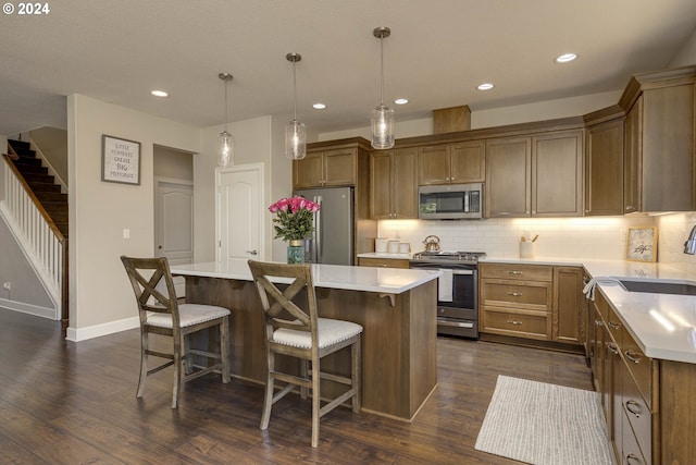 kitchen with a kitchen island, dark hardwood / wood-style floors, sink, decorative light fixtures, and appliances with stainless steel finishes