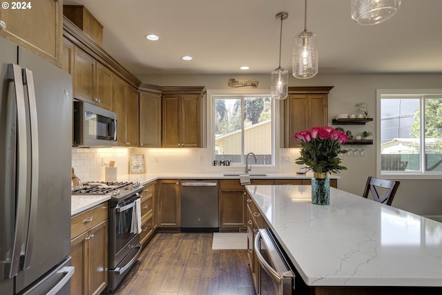 kitchen featuring dark hardwood / wood-style flooring, appliances with stainless steel finishes, a kitchen bar, sink, and light stone counters