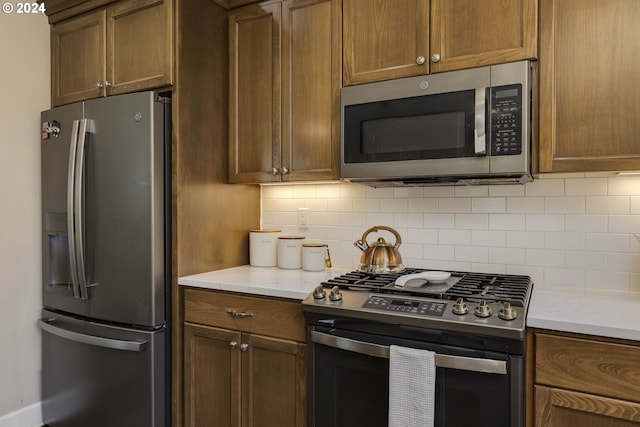 kitchen featuring light stone countertops, appliances with stainless steel finishes, and tasteful backsplash