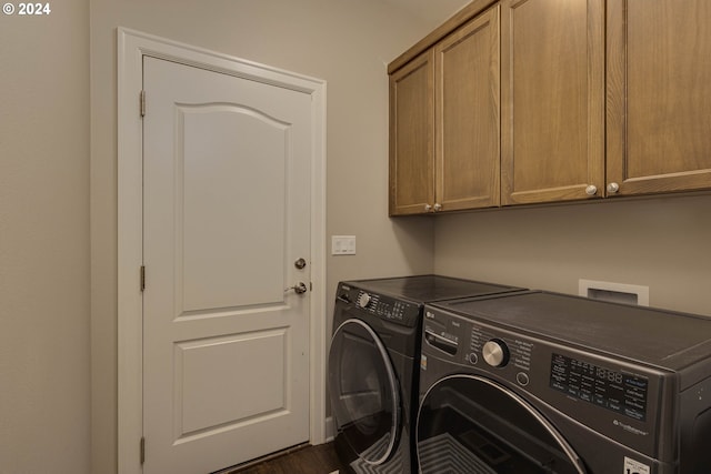 laundry room featuring dark hardwood / wood-style flooring, washing machine and dryer, and cabinets