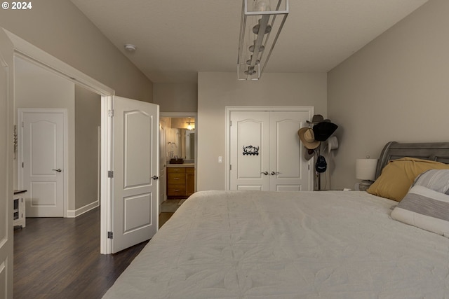 bedroom with a closet, ensuite bath, and dark wood-type flooring