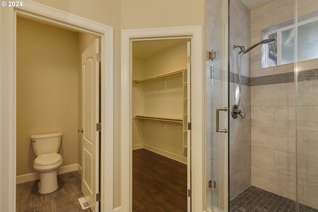 bathroom with a shower with door, toilet, and hardwood / wood-style flooring